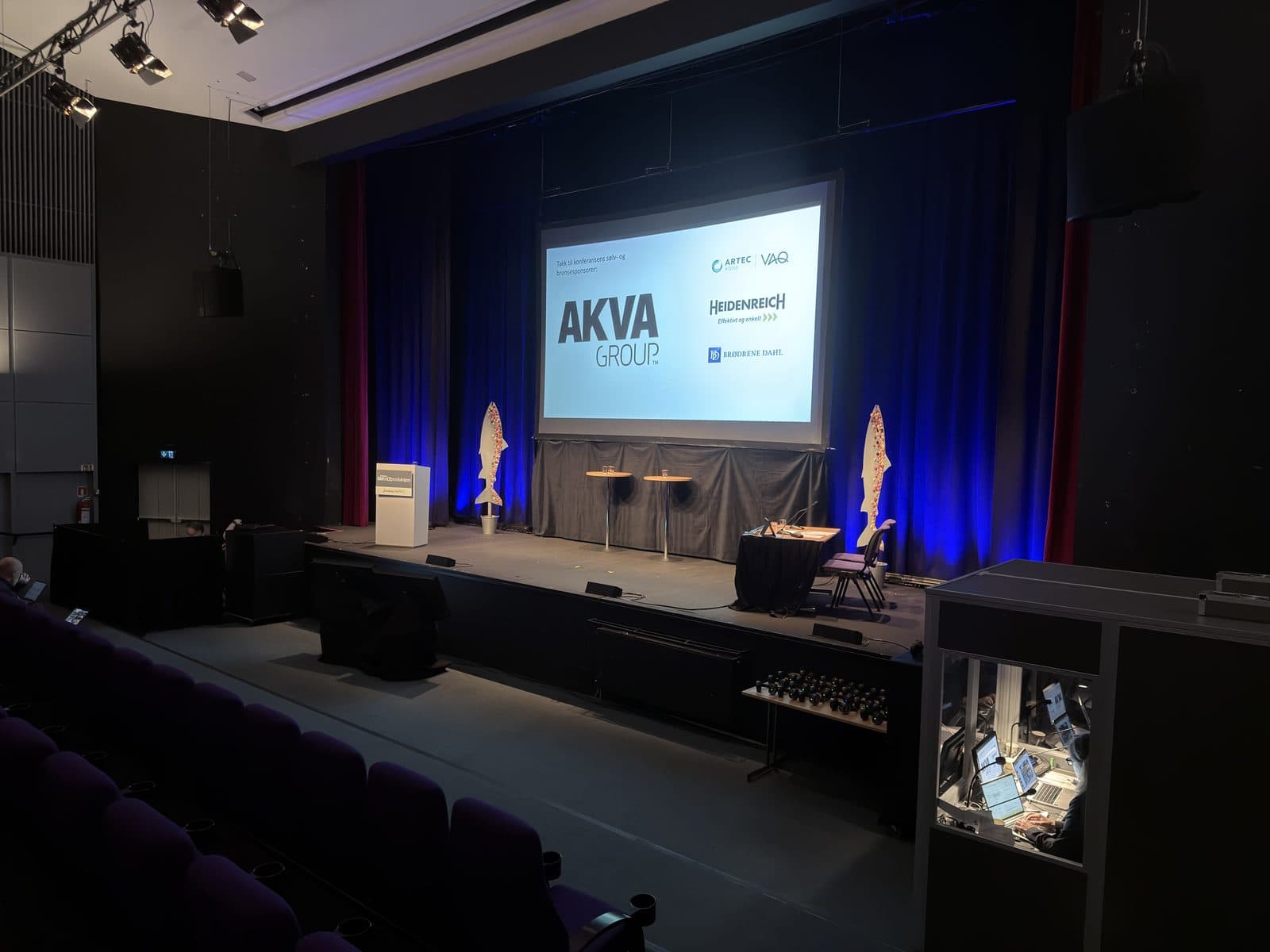 Conference hall with a stage, receiver headsets in front of the stage, and an interpretation setup in the room