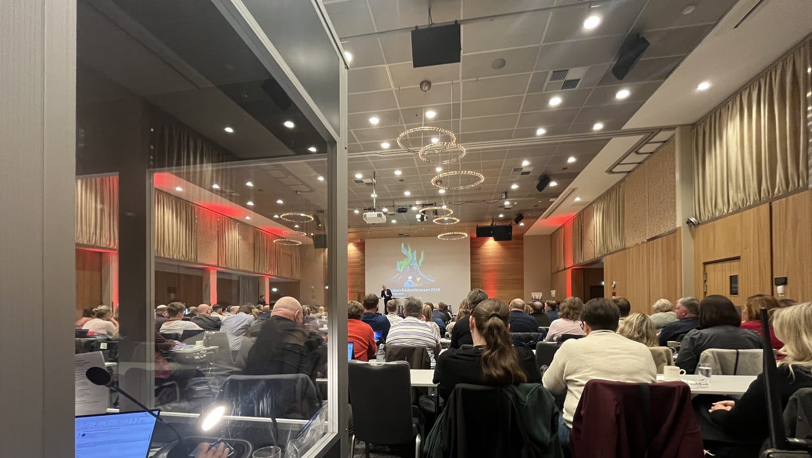 Utsikt fra en tolkekabin ut mot en fullsatt konferansesal